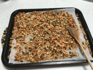 Granola fatta in casa: teglia con mestolo di legno e granola tostata