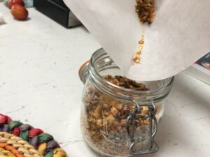 Granola fatta in casa versata in un contenitore di vetro ermetico con l'ausilio di carta da forno