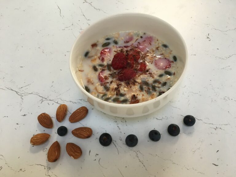 ciotola con latte freddo, granola fatta in casa, frutta fresca e scaglie di cioccolato. Mirtilli e mandorle per decorare.